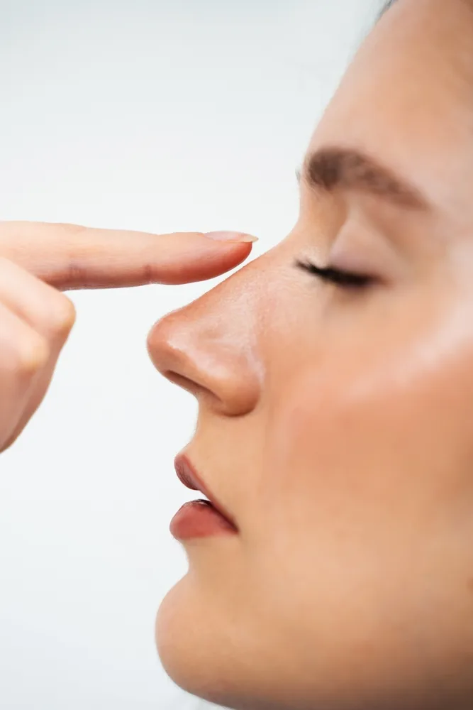 Patient pointing to nose in profile view during consultation