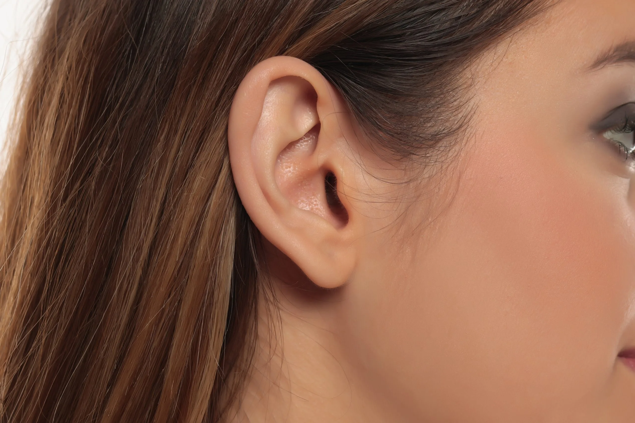 Close-up of woman's ear and long brown hair from side view