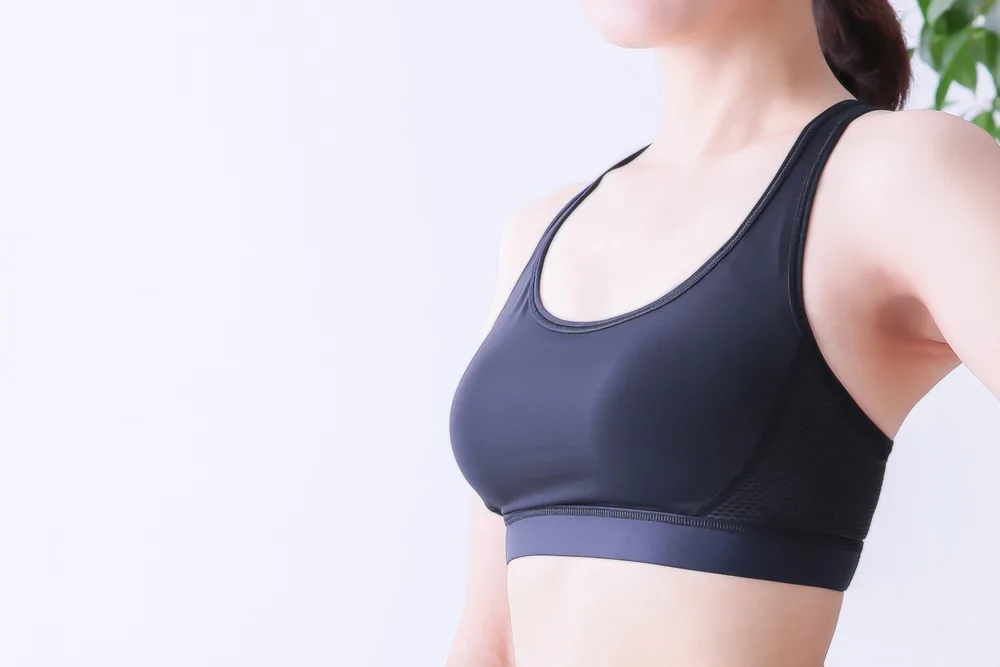 Woman in dark sports bra viewed from the side showing torso and shoulder