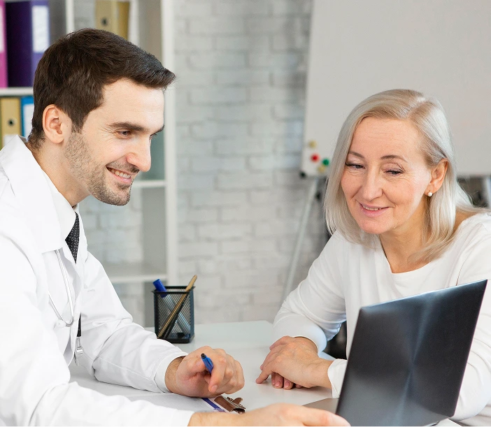 Male physician and older female patient reviewing information on laptop together