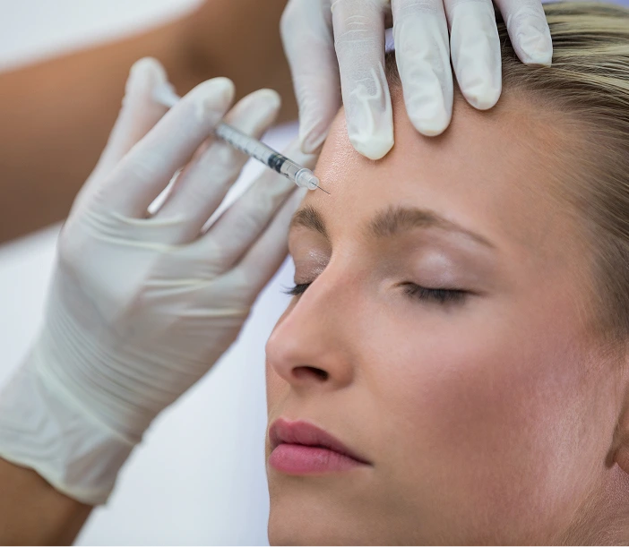 Practitioner injecting Botox into patient's forehead with gloved hands