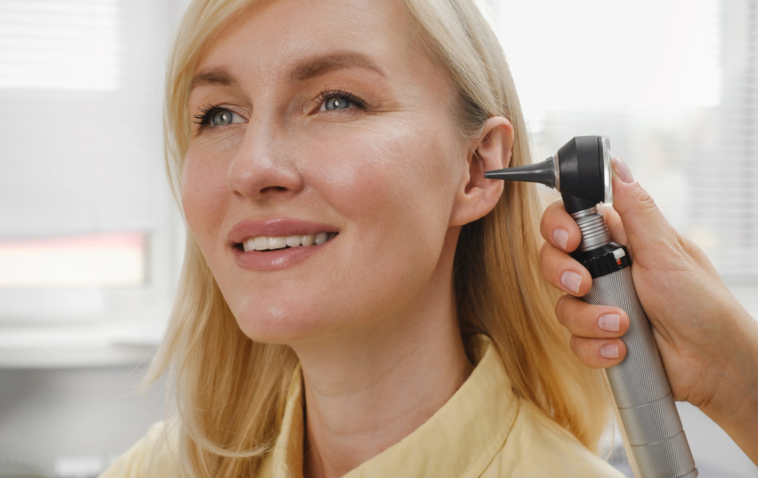 Provider using otoscope to examine patient's ear during clinical evaluation