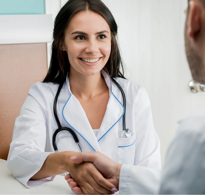 Female physician in white coat with stethoscope shaking hands with patient