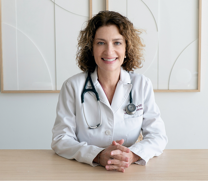 Dr. Yael Myers in white coat with stethoscope at desk