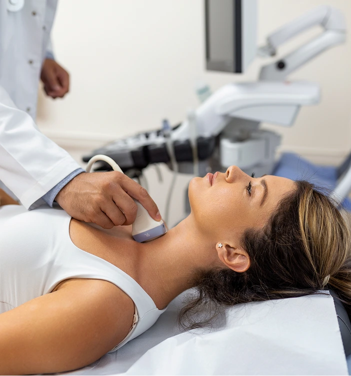 Provider performing ultrasound treatment on patient's neck in medical setting