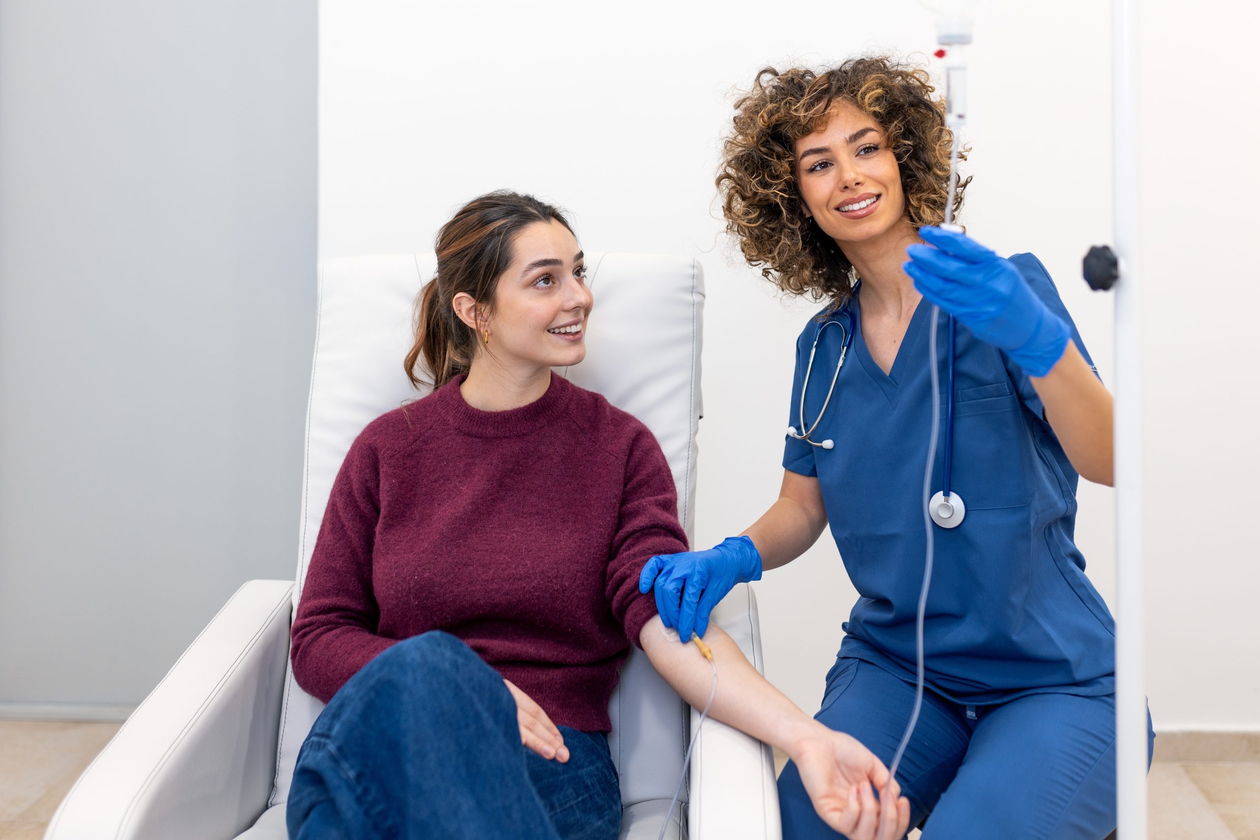 Nurse in blue scrubs examining patient's arm during medical appointment in clinic setting