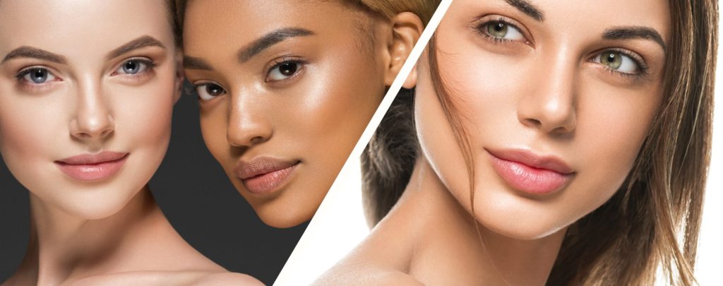 Three women with different skin tones smiling at camera